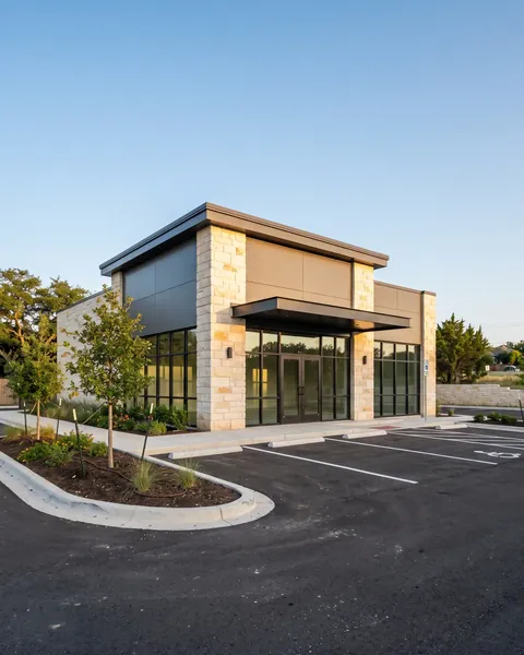 A newly finished commercial building with limestone columns, dark metal panels and a glass storefront